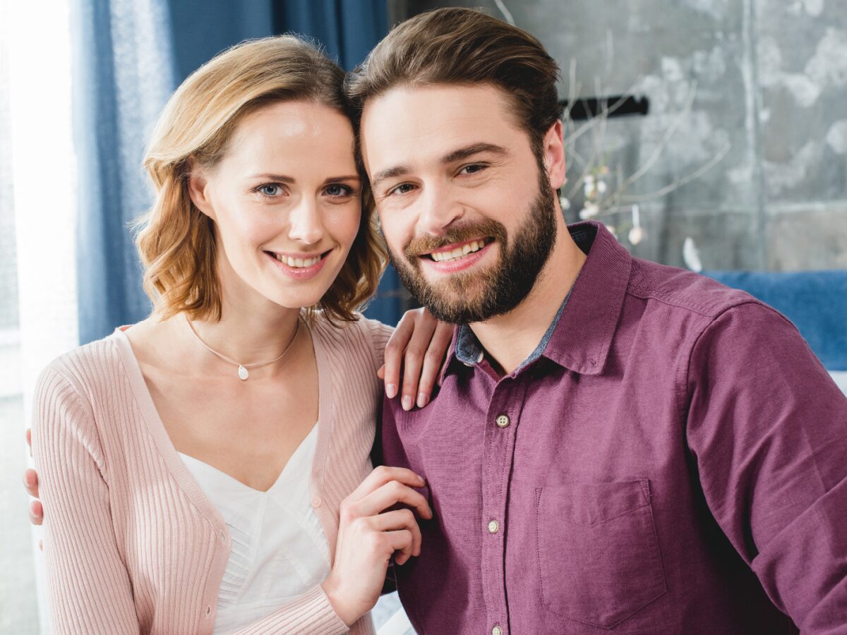 Smiling couple in NYC sitting together, representing support and connection through ADHD marriage counseling